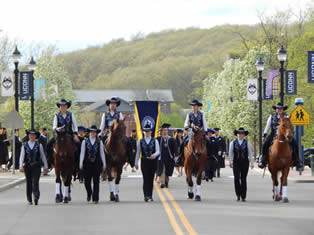 Students walking and riding horses in unison for 2015 Commencement
