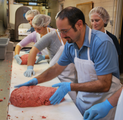 Faculty providing hands-on instruction in meat lab