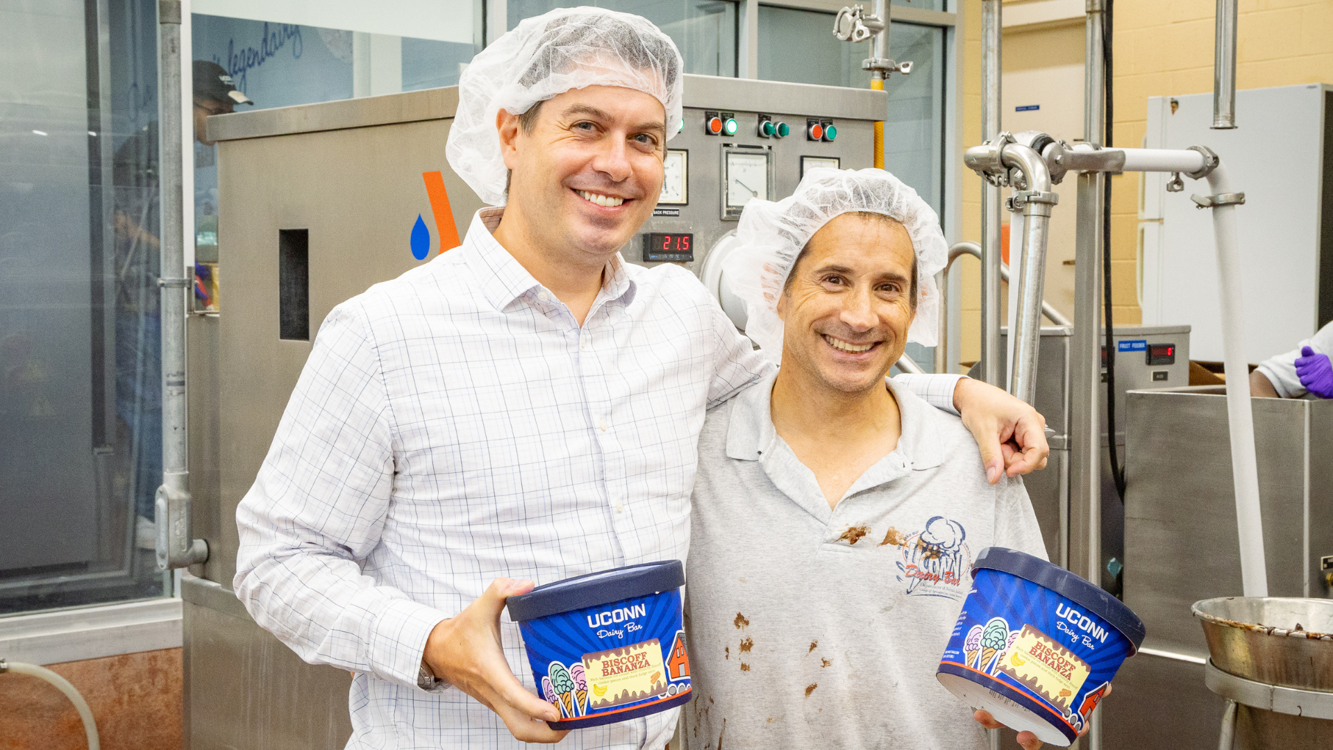 Group posing for photo while holding ice cream cartons inside of a creamery plant.