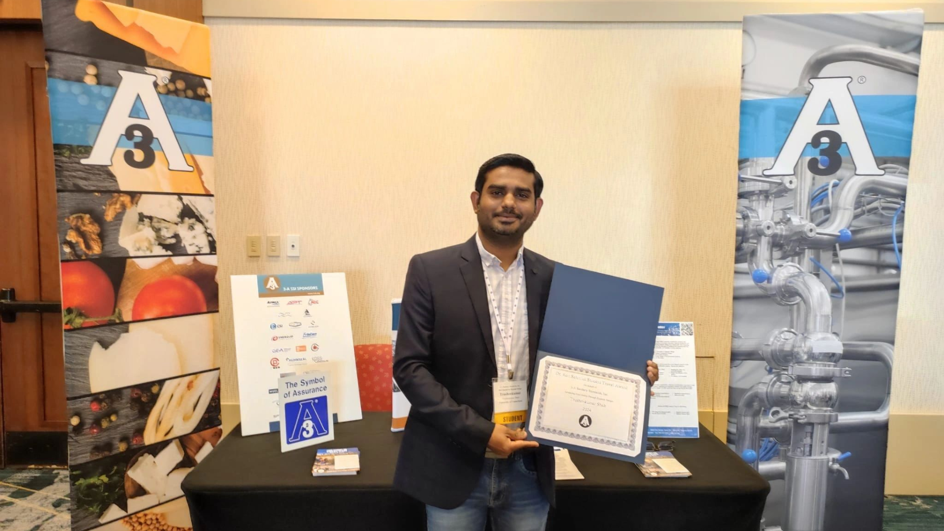 Trushenkumar Shah posing for a photo while holding up a plaque.