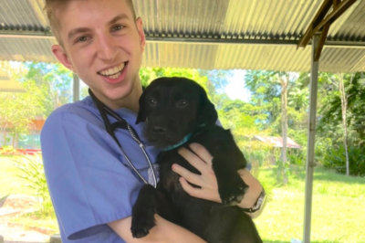 Undergraduate posing with dog outside of a vet clinic office