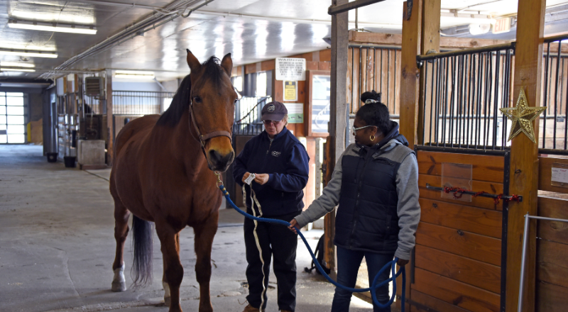 Jenifer Nadeau assisting a student with leading a horse