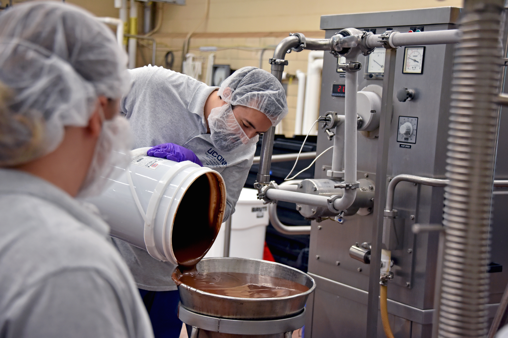 Creamery staff pouring ice cream mixture into machine